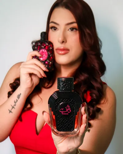 Aninha segurando dois perfumes árabes pretos e rosa